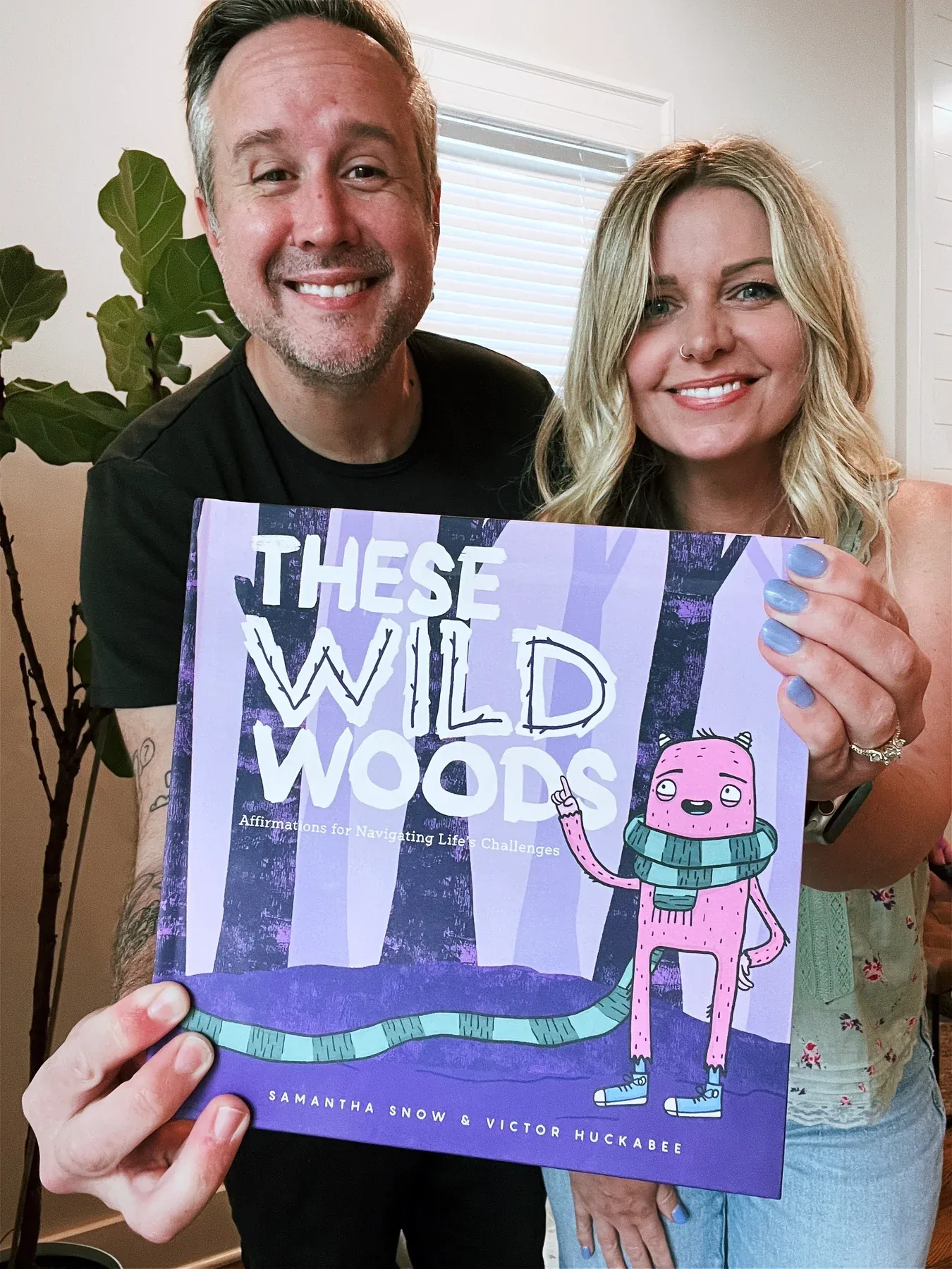 Victor Huckabee and Samantha Snow holding the finished These Wild Woods book